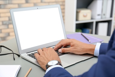 Photo of Man in office wear using laptop at table indoors