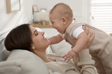 Photo of Happy young mother with her baby on sofa in living room