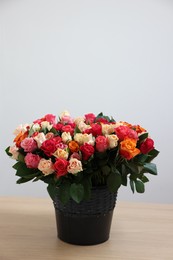 Photo of Bouquet of beautiful roses on wooden table against light background. Space for text