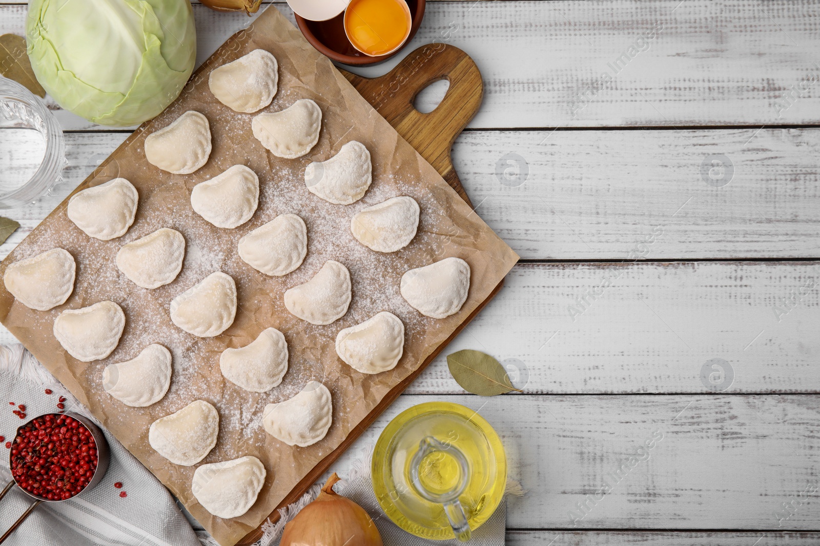 Photo of Raw dumplings (varenyky) with tasty filling and ingredients on white wooden table, flat lay. Space for text