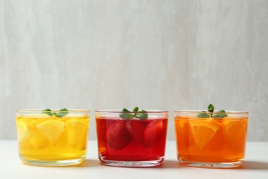 Photo of Glass bowls of natural jelly desserts on light table, space for text