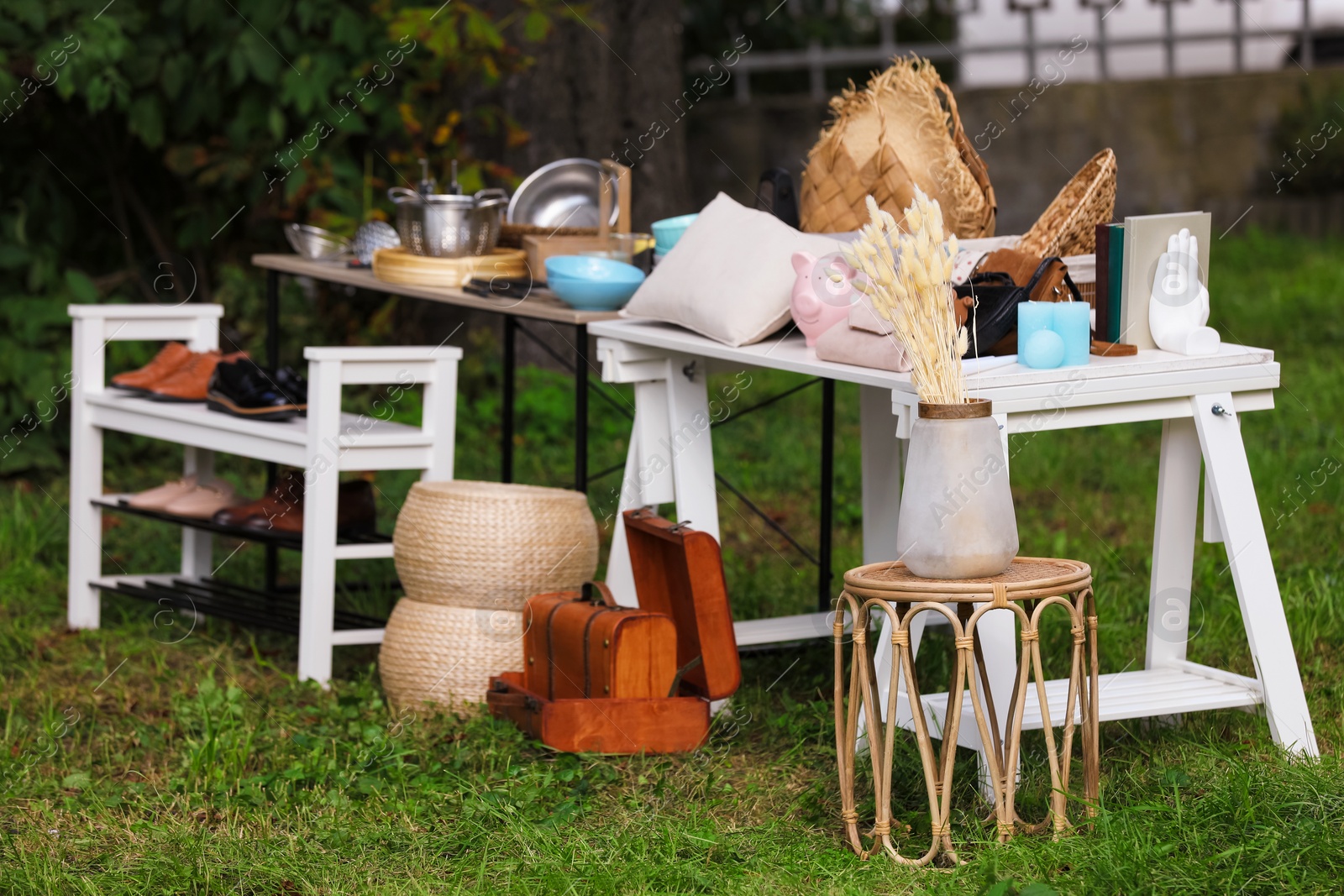 Photo of Small tables with many different items on garage sale in yard