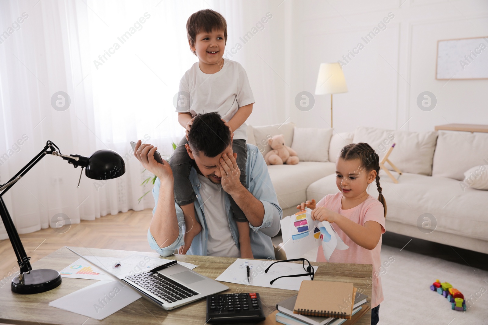 Photo of Overwhelmed man combining parenting and work at home