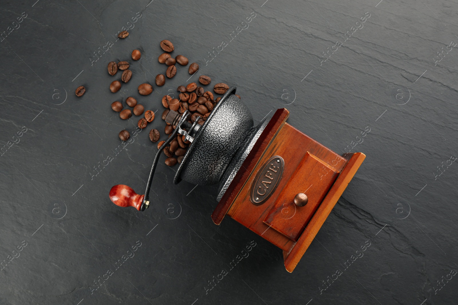Photo of Vintage manual coffee grinder with beans on black table, flat lay