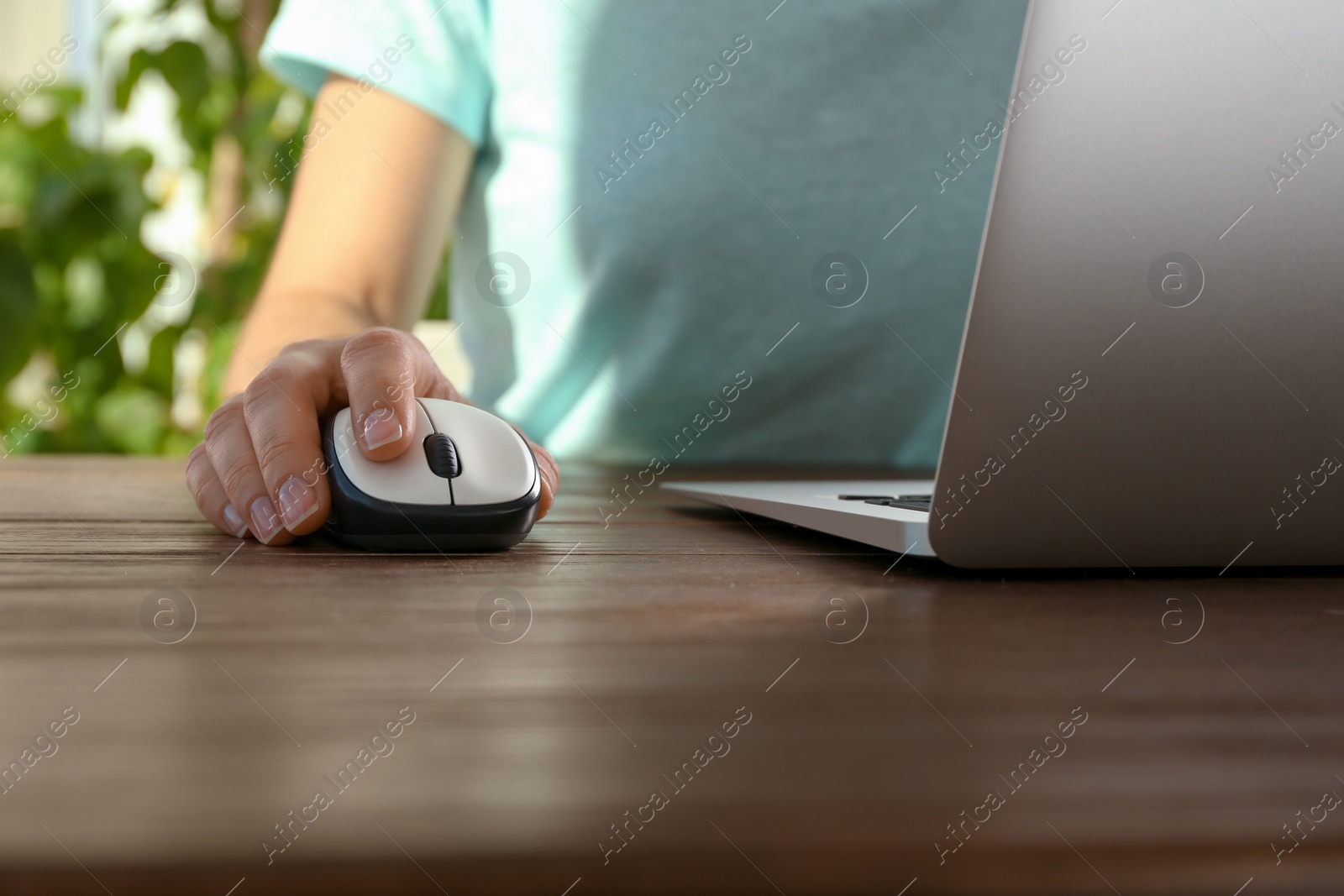 Photo of Woman using computer mouse with laptop at table, closeup