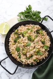 Photo of Tasty fried rice with vegetables served on white marble table, flat lay