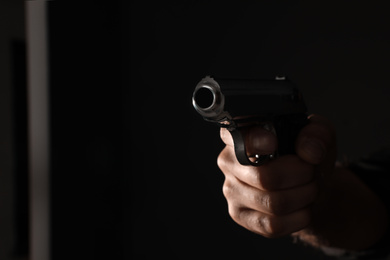 Photo of Professional killer with gun on black background, closeup. Space for text