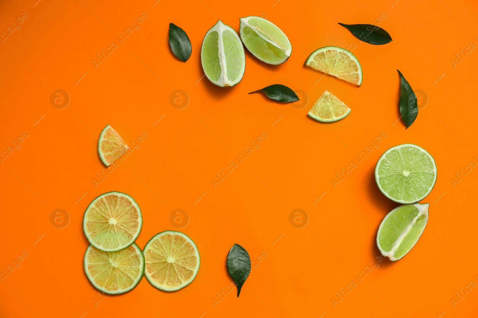 Photo of Flat lay composition with cut fresh juicy limes on orange background. Space for text