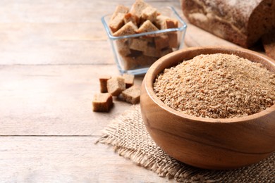 Fresh breadcrumbs in bowl on wooden table. Space for text