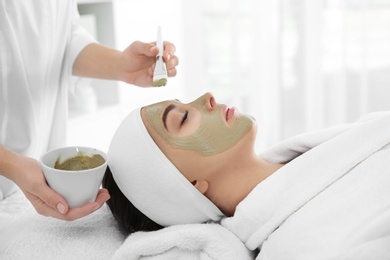 Photo of Cosmetologist applying mask on client's face in spa salon