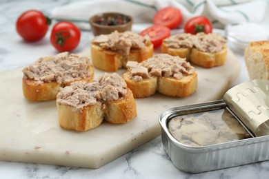 Photo of Tasty sandwiches with cod liver on white marble table