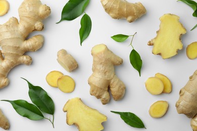 Photo of Fresh ginger with green leaves on white background, flat lay