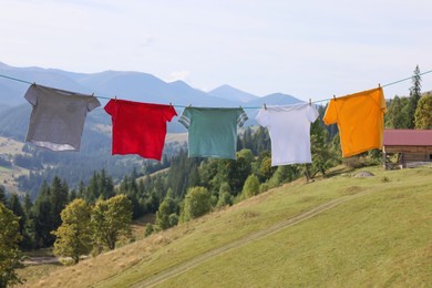 Photo of Washing line with clean laundry and clothespins in mountains