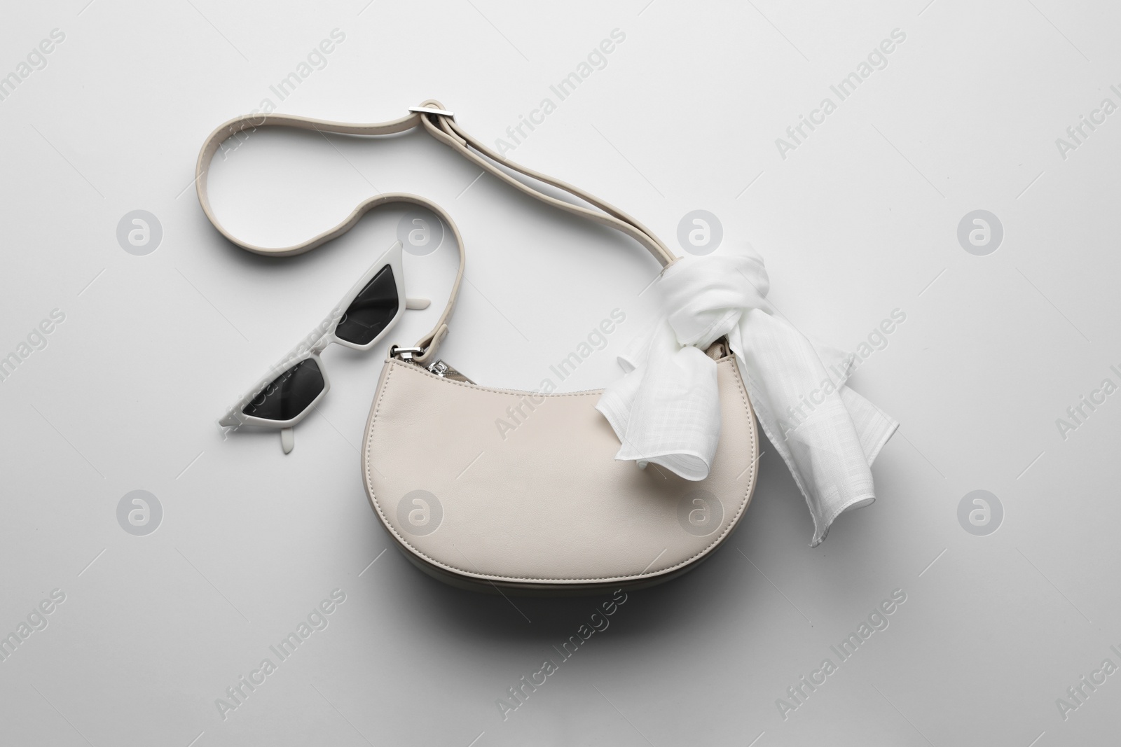 Photo of Stylish woman's bag and sunglasses on light background, flat lay