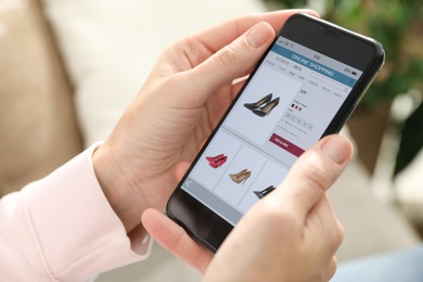 Photo of Woman using smartphone for online shopping indoors, closeup
