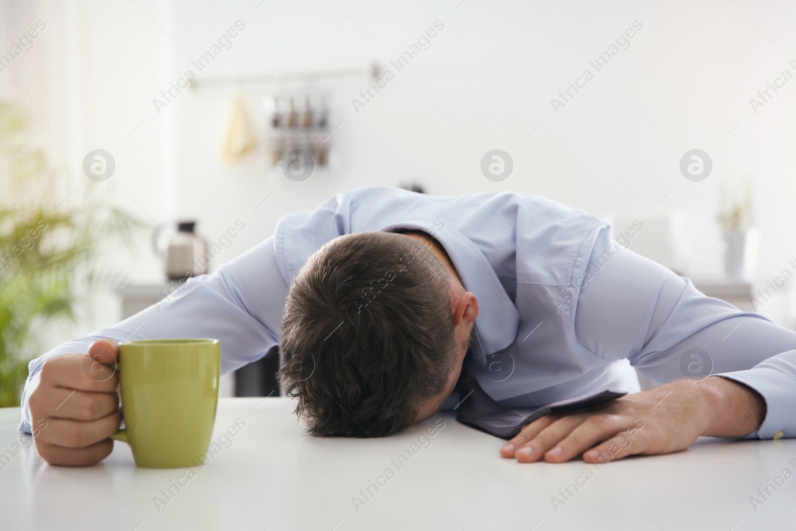 Photo of Man with cup of drink sleeping at home in morning