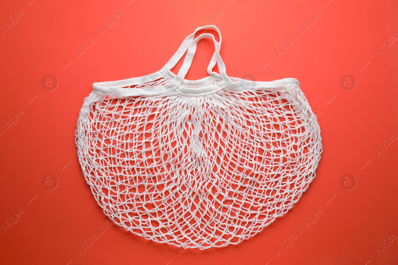 Photo of White string bag on red background, top view