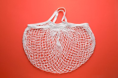 Photo of White string bag on red background, top view