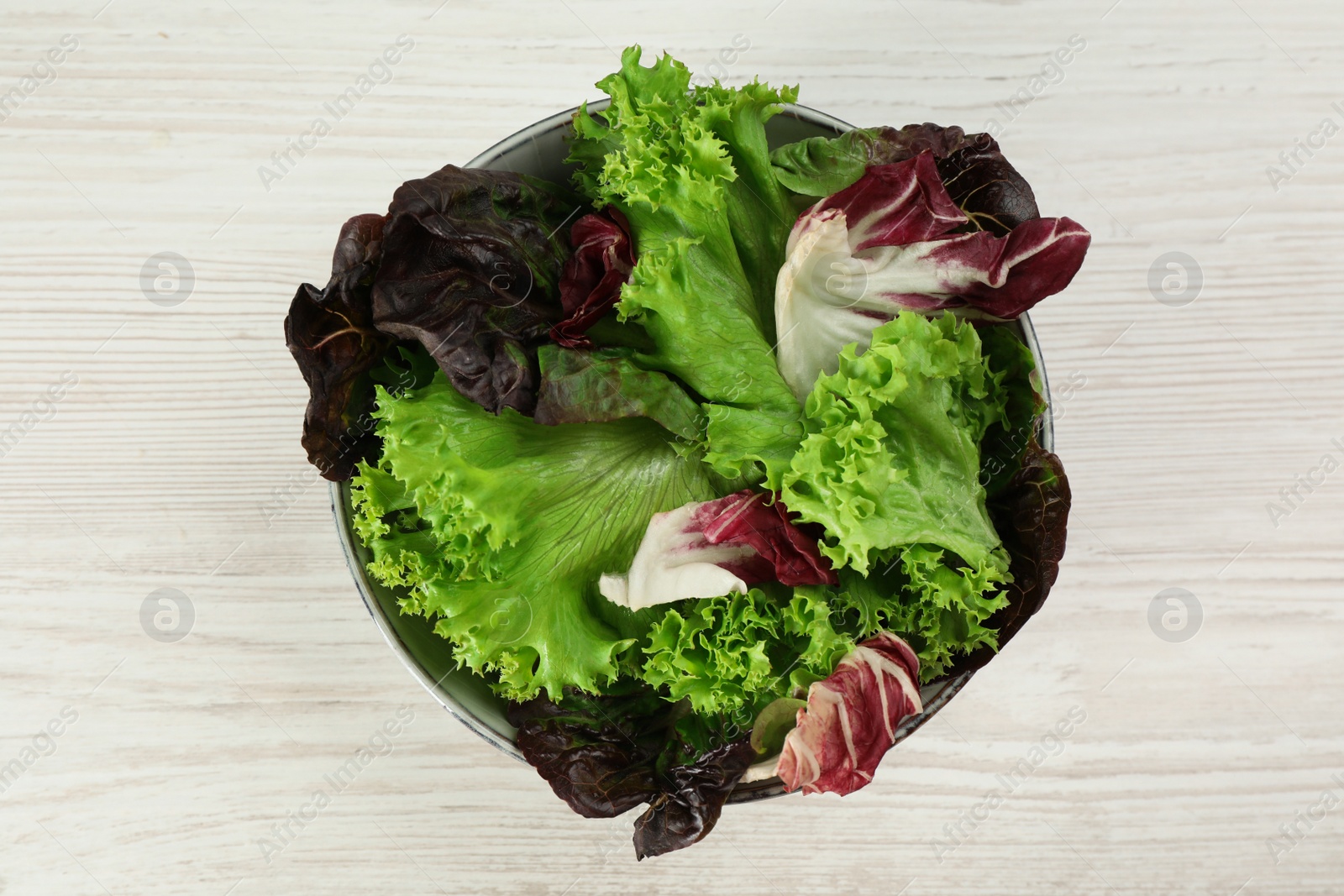 Photo of Different sorts of lettuce on white wooden table, top view