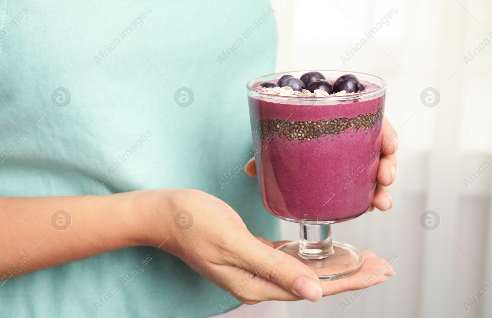 Photo of Woman holding glass with tasty acai smoothie, closeup