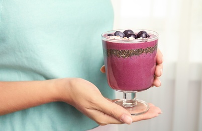 Photo of Woman holding glass with tasty acai smoothie, closeup