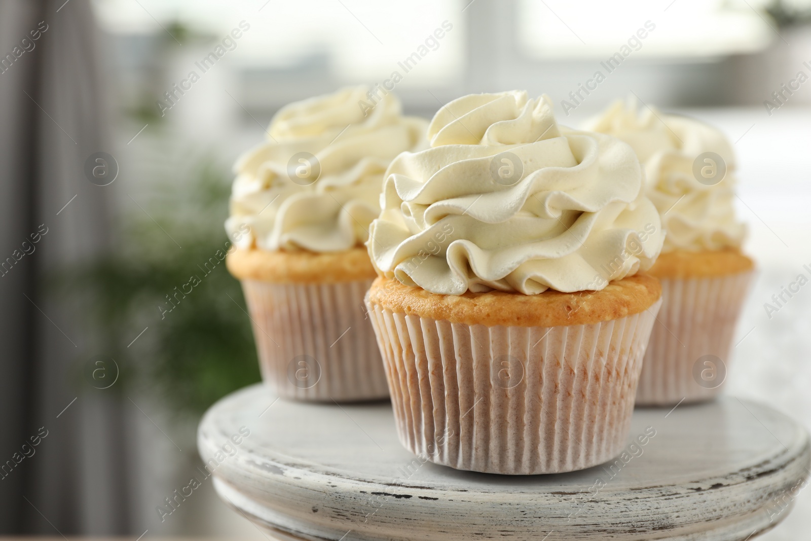 Photo of Tasty cupcakes with vanilla cream on stand, closeup