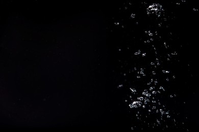 Photo of Air bubbles in water on black background, space for text