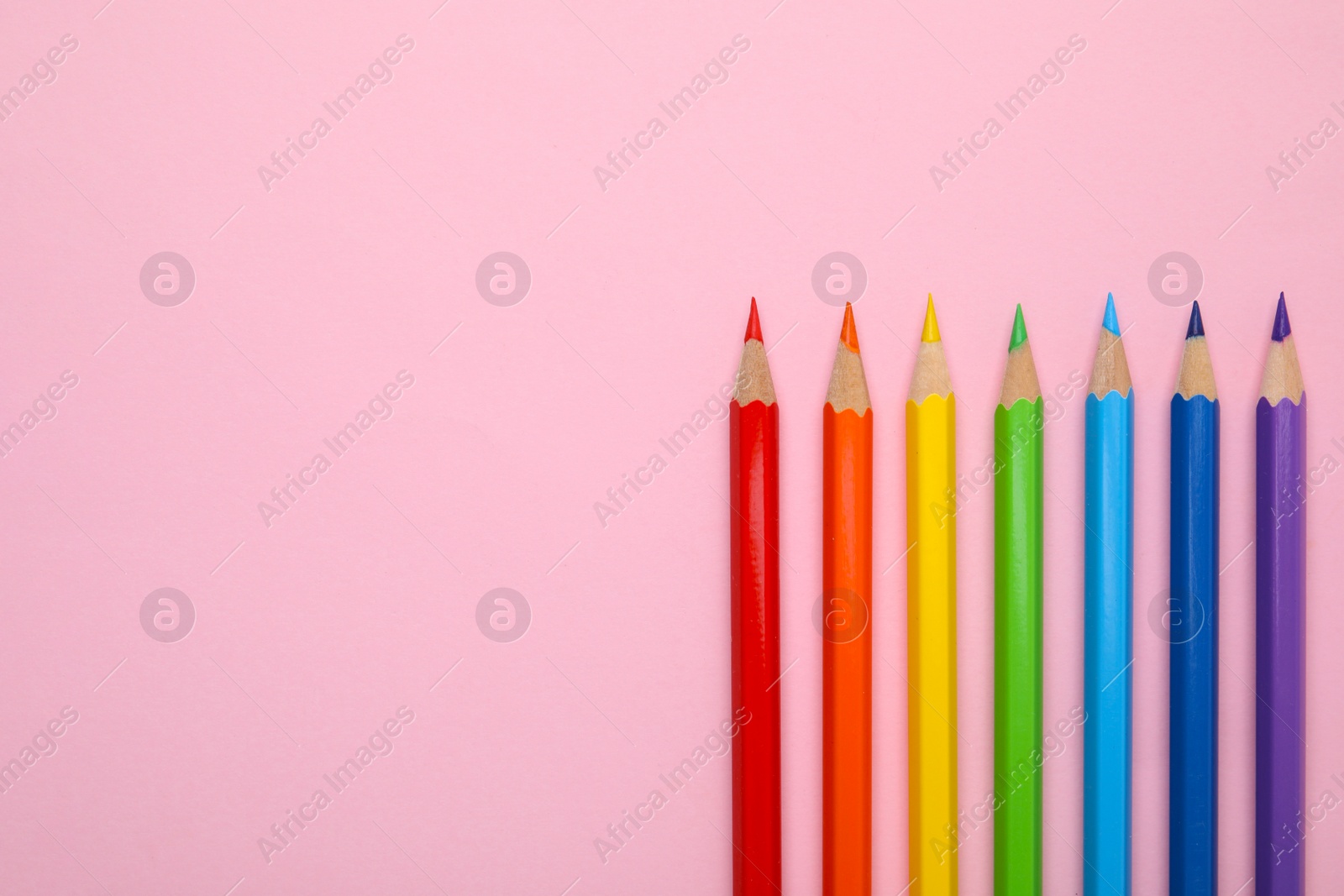 Photo of Colorful wooden pencils on pink background, flat lay. Space for text