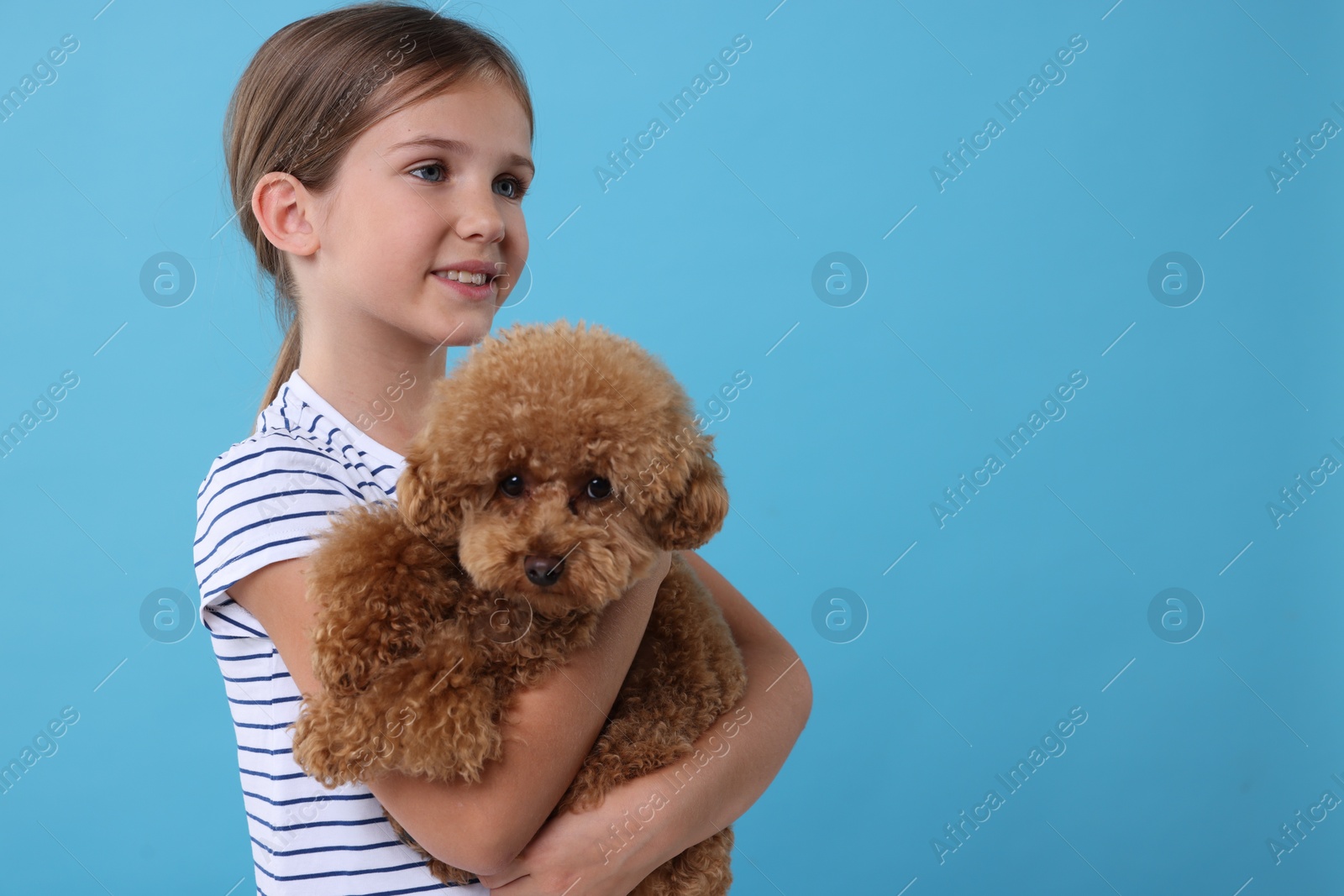 Photo of Little child with cute puppy on light blue background, space for text. Lovely pet