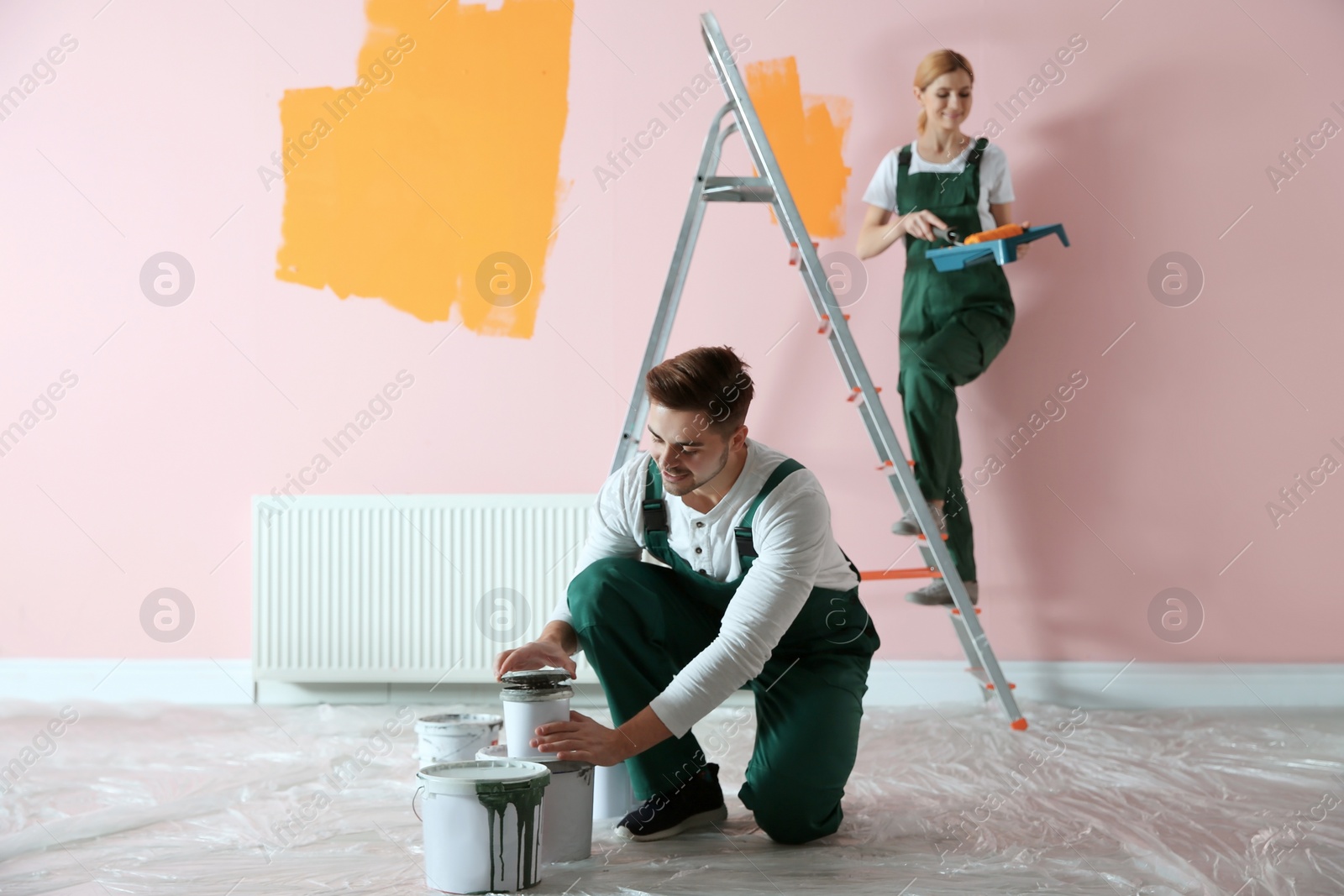 Photo of Professional decorators painting wall indoors. Home repair service