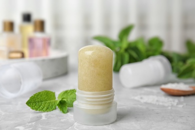 Natural crystal alum deodorant and mint on light grey marble table