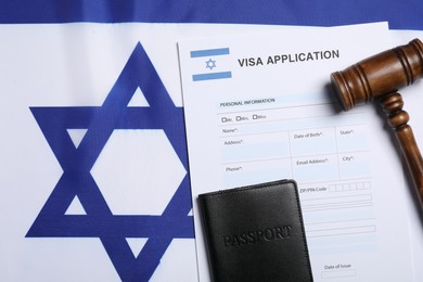 Immigration to Israel. Visa application form, gavel and passport on flag, flat lay. Space for text