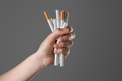 Stop smoking concept. Woman holding cigarettes on gray background, closeup with space for text