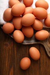 Raw brown chicken eggs on wooden table, flat lay
