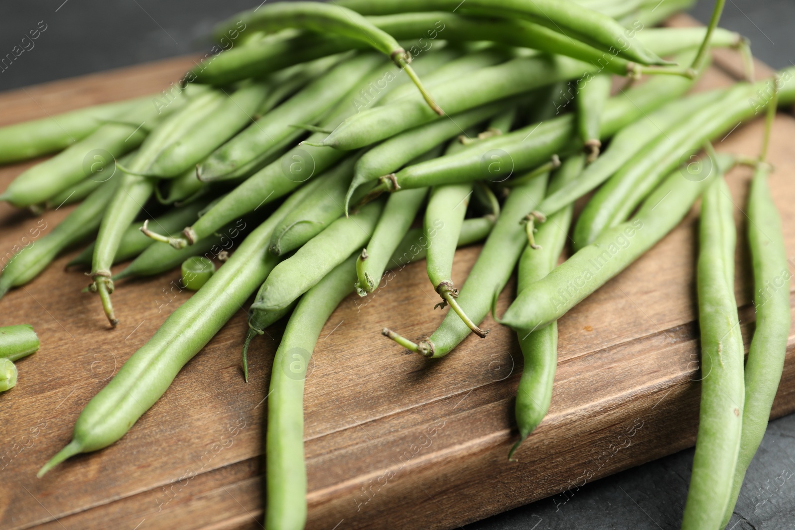 Photo of Fresh green beans on wooden board, closeup