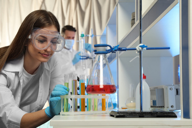 Photo of Scientist taking test tube from rack indoors. Laboratory analysis