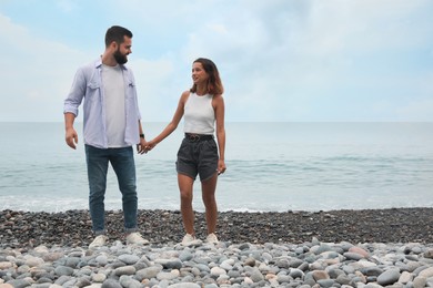 Photo of Happy young couple on beach near sea. Space for text
