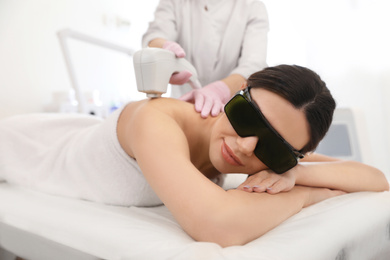 Photo of Young woman undergoing laser epilation procedure in beauty salon