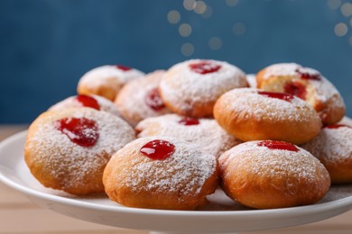 Hanukkah donuts with jelly and powdered sugar on stand against blurred festive lights, closeup