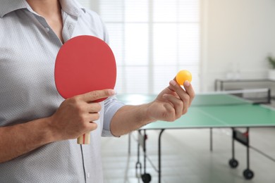 Photo of Businessman with tennis racket and ball near ping pong table in office, closeup