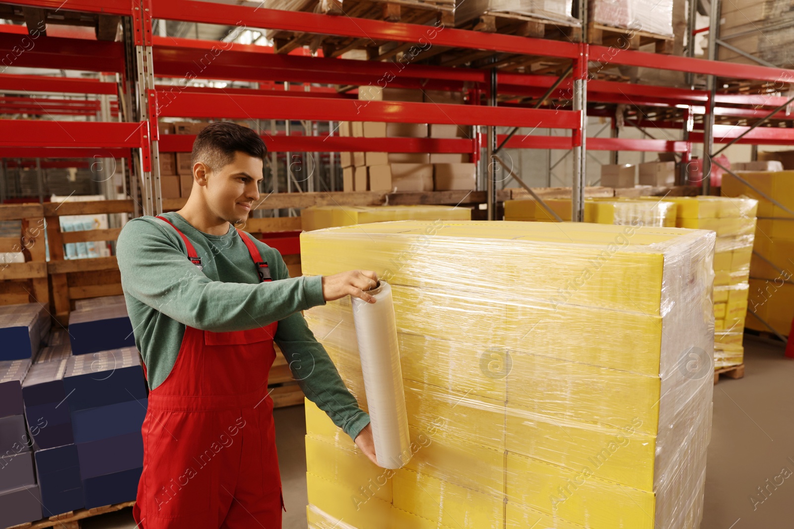 Photo of Worker wrapping boxes in stretch film at warehouse