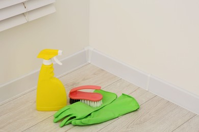 Spray bottle of cleaning product, rubber gloves and brush indoors