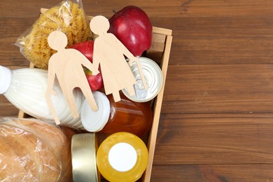 Photo of Humanitarian aid for elderly people. Different donation food products and figures of senior couple on wooden table, top view. Space for text