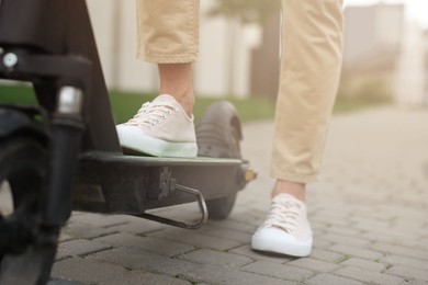 Photo of Man with modern kick scooter on city street, closeup