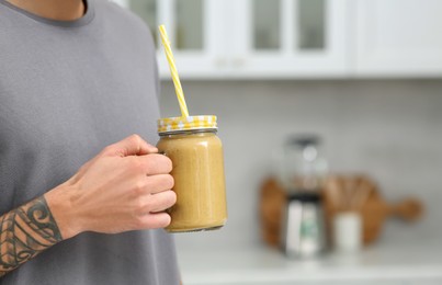 Photo of Man with delicious smoothie in kitchen, closeup. Space for text