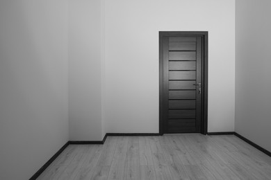 Empty renovated room with white walls and black door