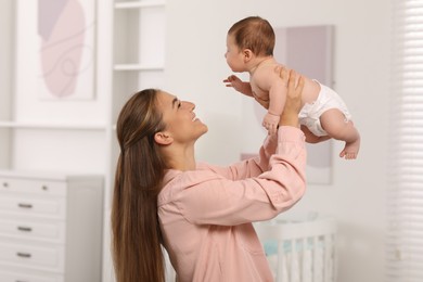 Photo of Mother having fun her cute newborn baby in child's room