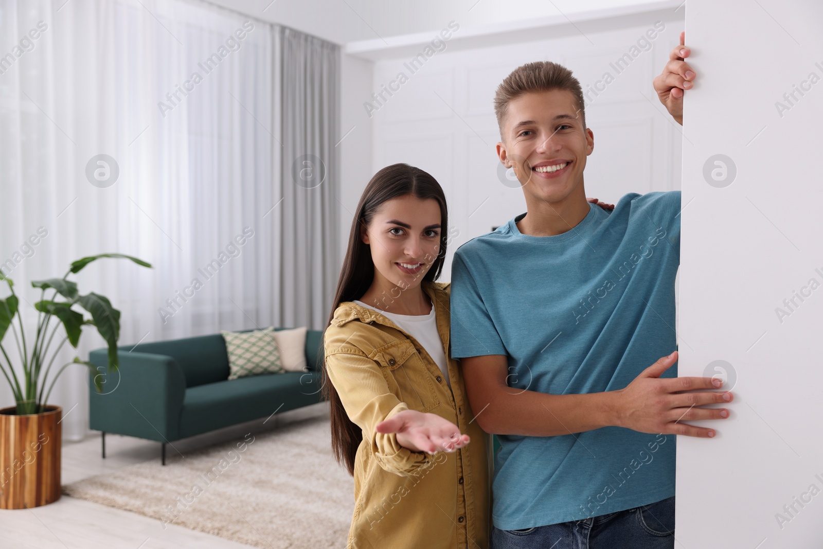 Photo of Happy couple welcoming near white wall at home, space for text. Invitation to come in room