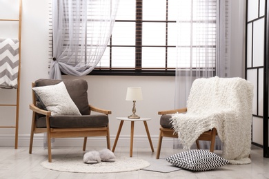 Cozy interior with armchairs, pillows and plaid near window