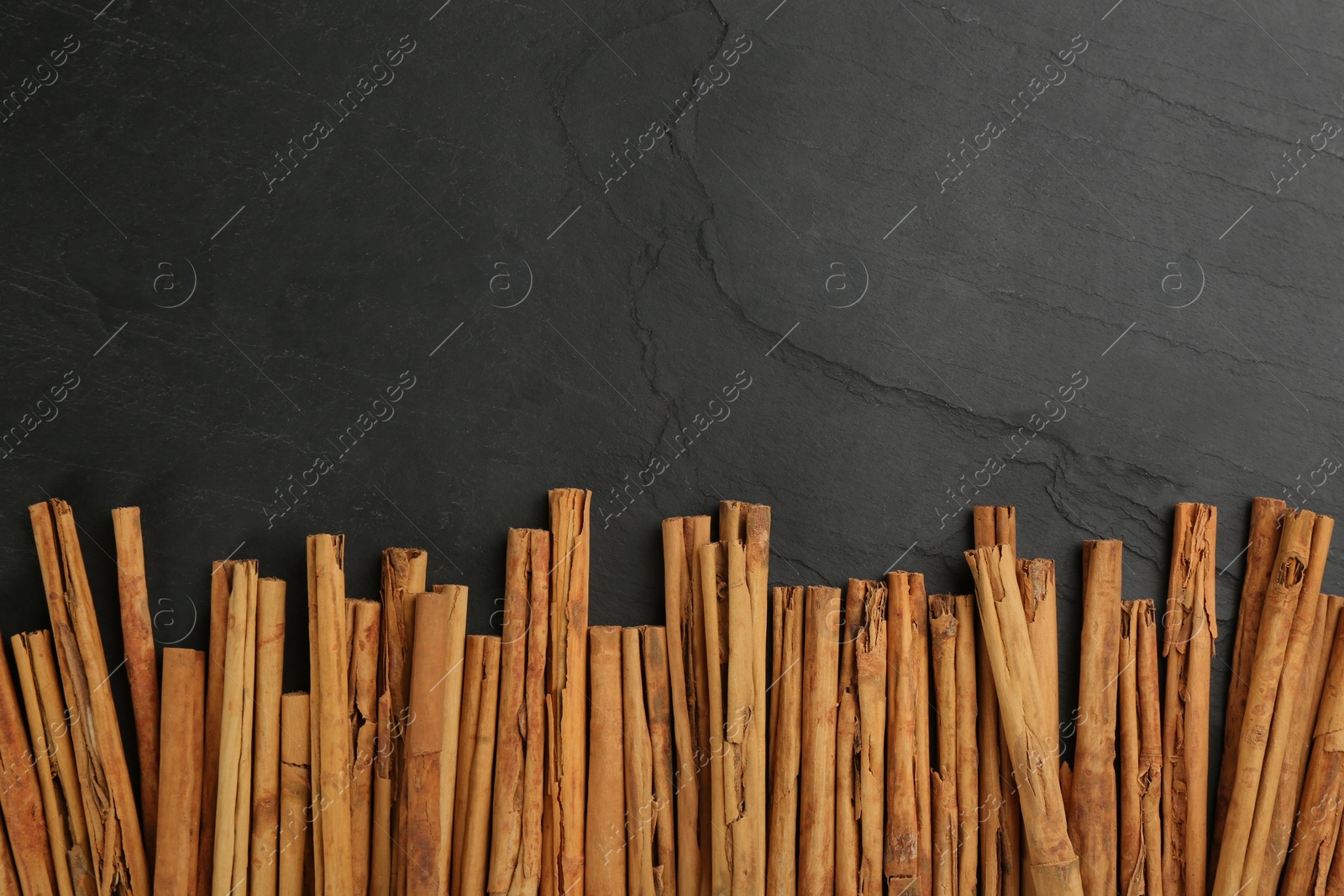 Photo of Aromatic cinnamon sticks on black table, flat lay. Space for text